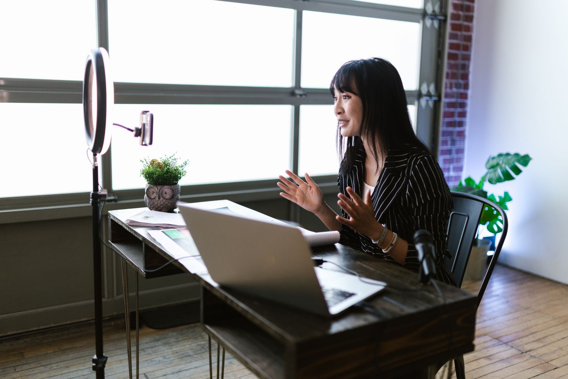 Woman engaging with audience through vlogging setup in stylish office space.