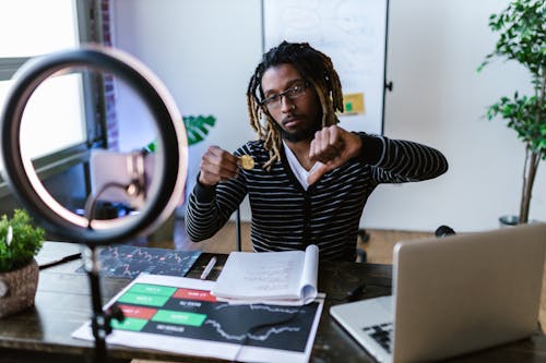 A Man Holding Bitcoin while Doing Thumbs Down