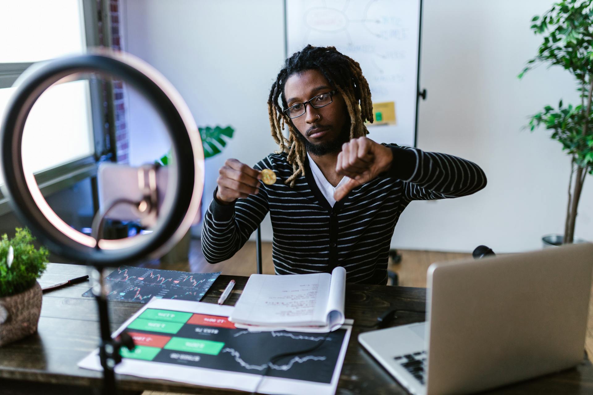 A Man Holding Bitcoin while Doing Thumbs Down