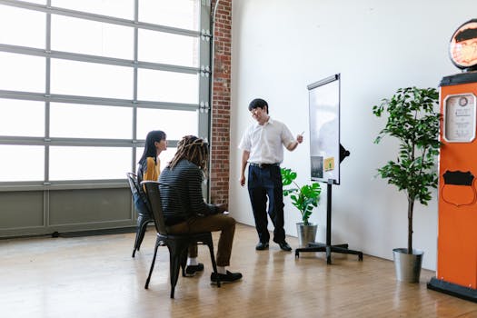 A meeting in a modern office with a presenter explaining concepts on a whiteboard.