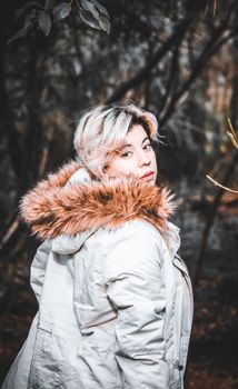 Portrait of a fashionable woman with a fur-trimmed coat in an outdoor setting.