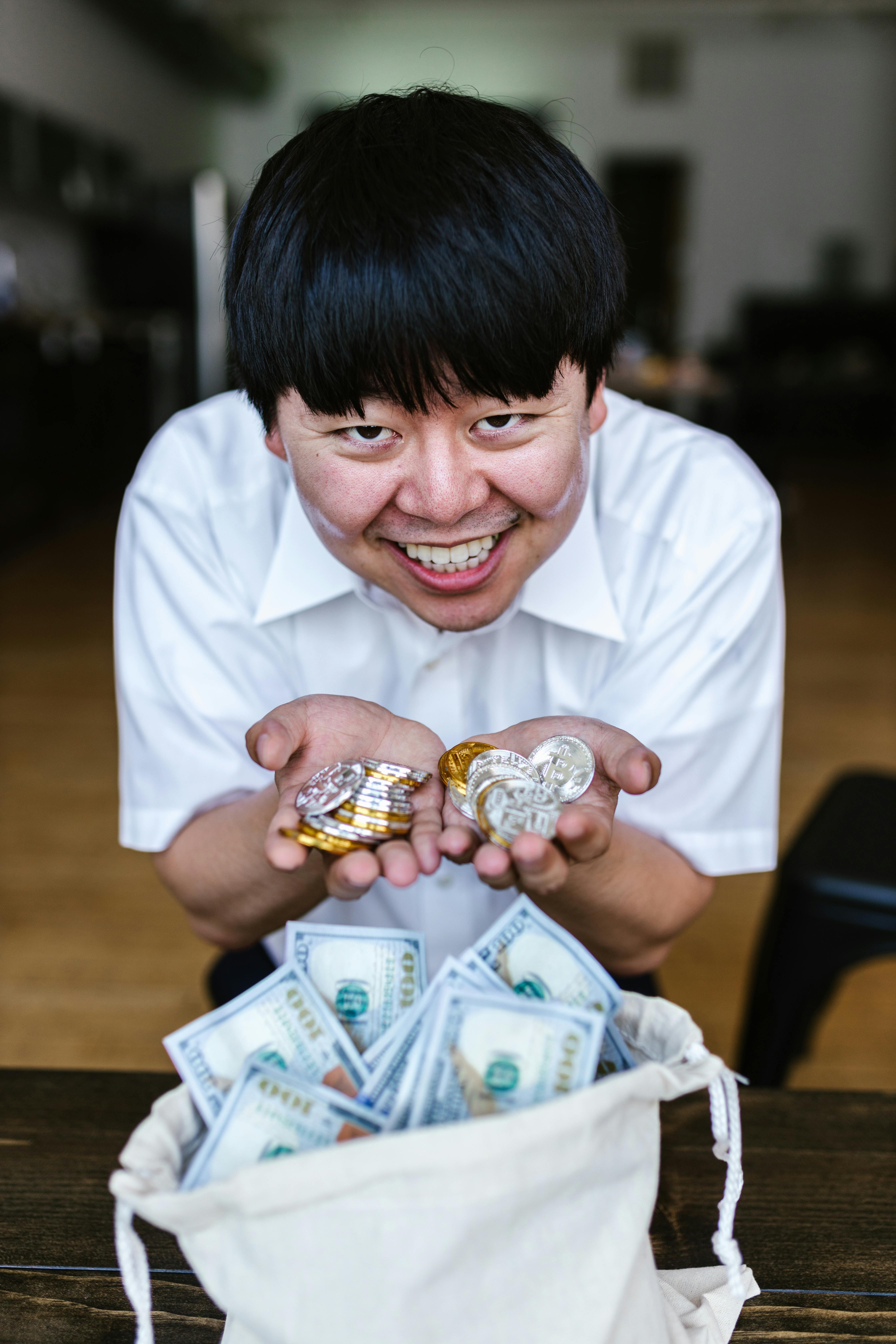 man in white button up shirt holding gold and silver coins