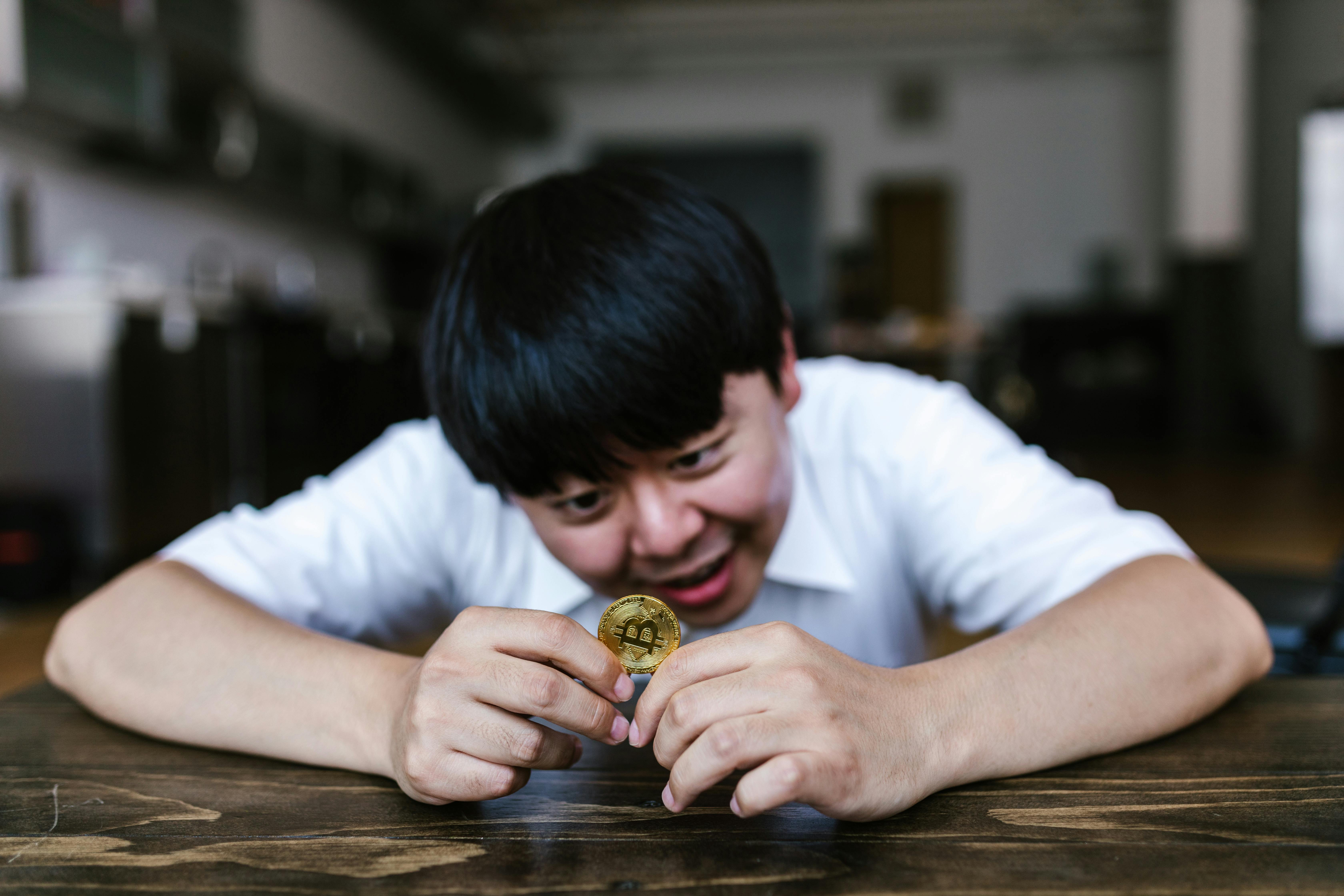 person in white t shirt holding gold round coin