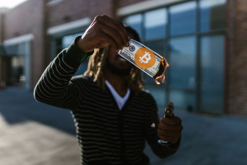 Free Man holding a burning dollar bill with Bitcoin symbol. Conceptual image of cryptocurrency impact. Stock Photo