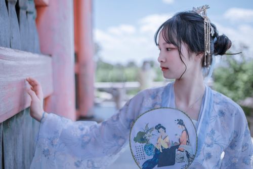 Free Beautiful woman in traditional hanfu, holding a fan, outdoors. Stock Photo