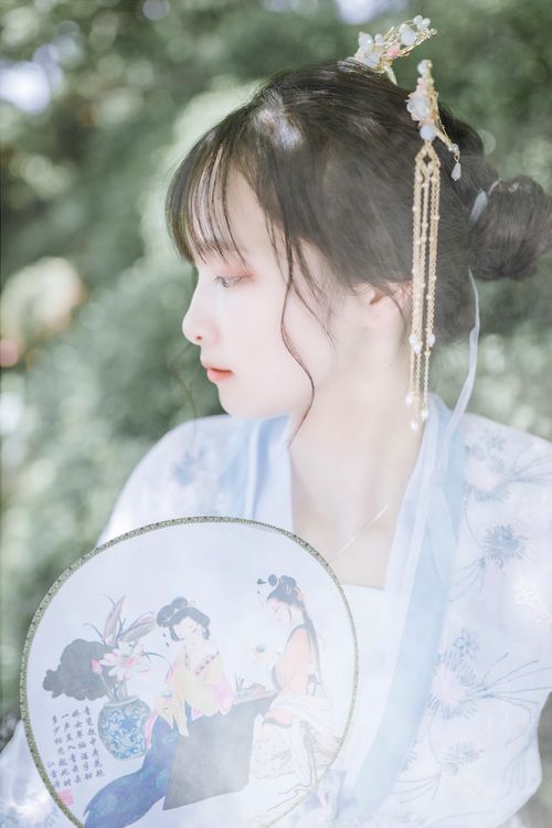 Free Elegant woman in traditional clothing holding a decorative fan, outdoors. Stock Photo