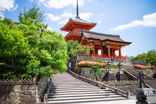 Free Scenic view of a traditional Japanese pagoda surrounded by lush greenery and clear blue sky. Stock Photo