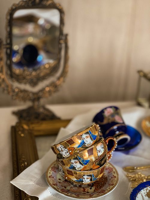 Free From above of dirty porcelain tea cups and saucers placed one on top of other near blurred vintage mirror Stock Photo