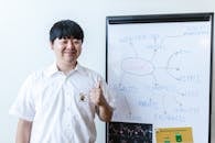 Man Showing a Thumbs Up Beside a White Board