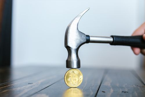 Free Close-up of a hammer poised above a Bitcoin coin on a wooden surface, representing cryptocurrency challenges. Stock Photo
