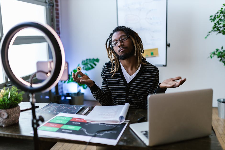 A man in a home office setting holds a bitcoin, discussing cryptocurrency trading.