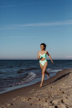 Woman enjoying a summer day running along a sandy beach by the ocean.