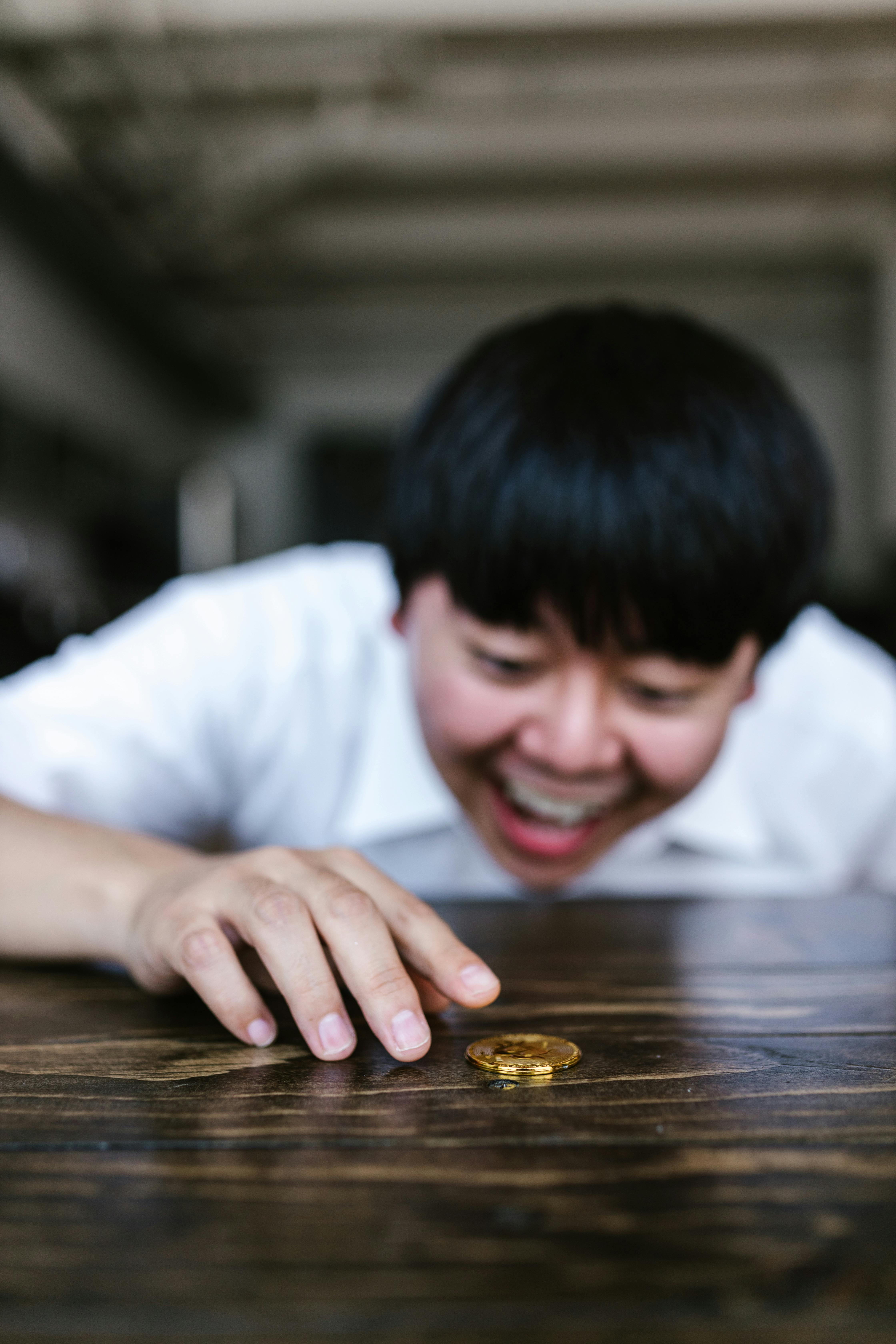 man in white shirt looking at the gold coin on the table