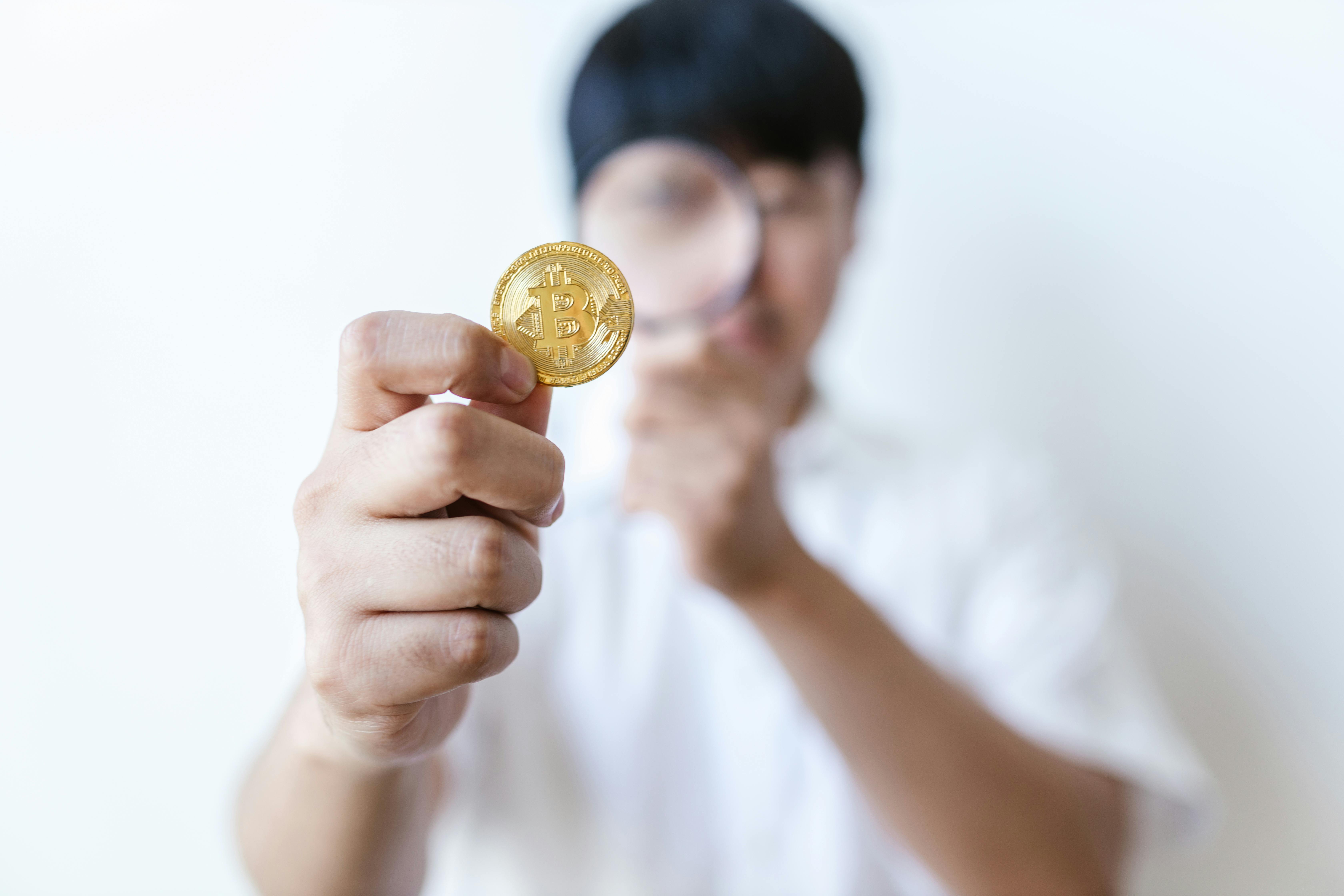 selective focus photo of gold coin held by a man