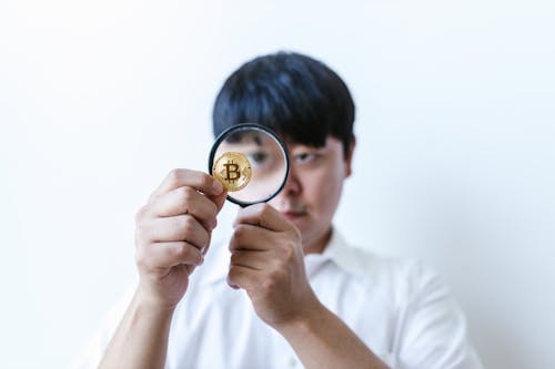 Free A Man Looking at a Coin Through a Magnifying Glass Stock Photo