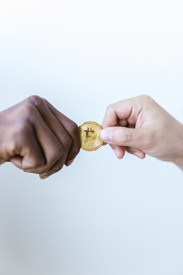 Close-Up Shot Of Two People Holding A Gold Coin