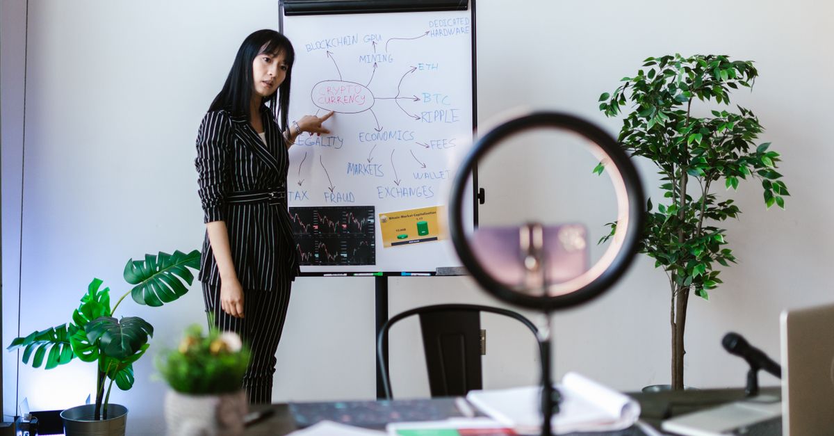 A person standing in front of a whiteboard with a business plan, while a small TV in the corner shows a viral video