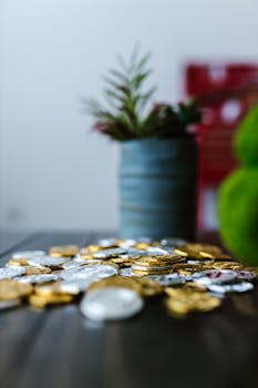 A stack of gold and silver coins with green plants in soft focus background.