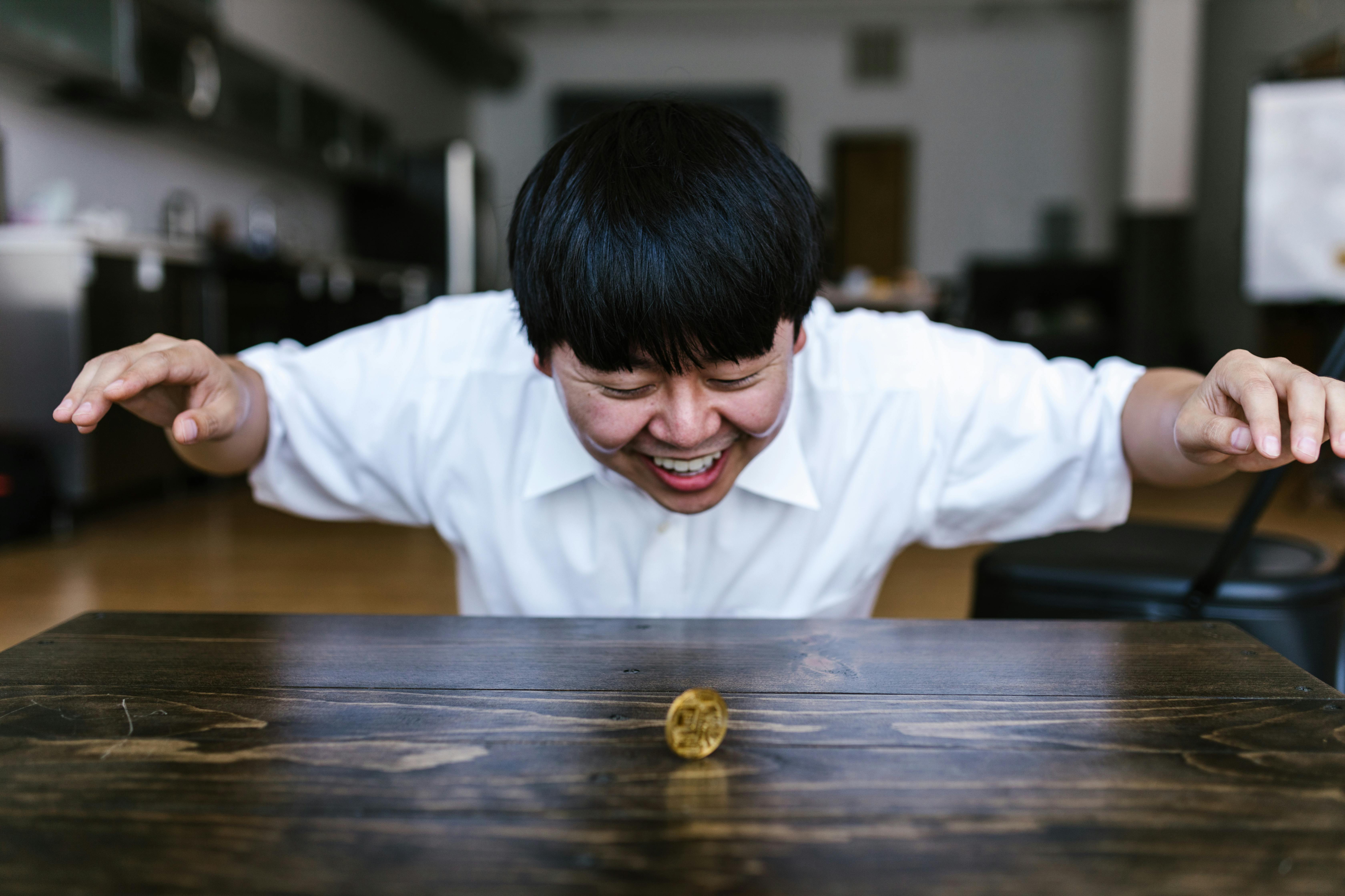 a happy man in white shirt looking at a gold coin