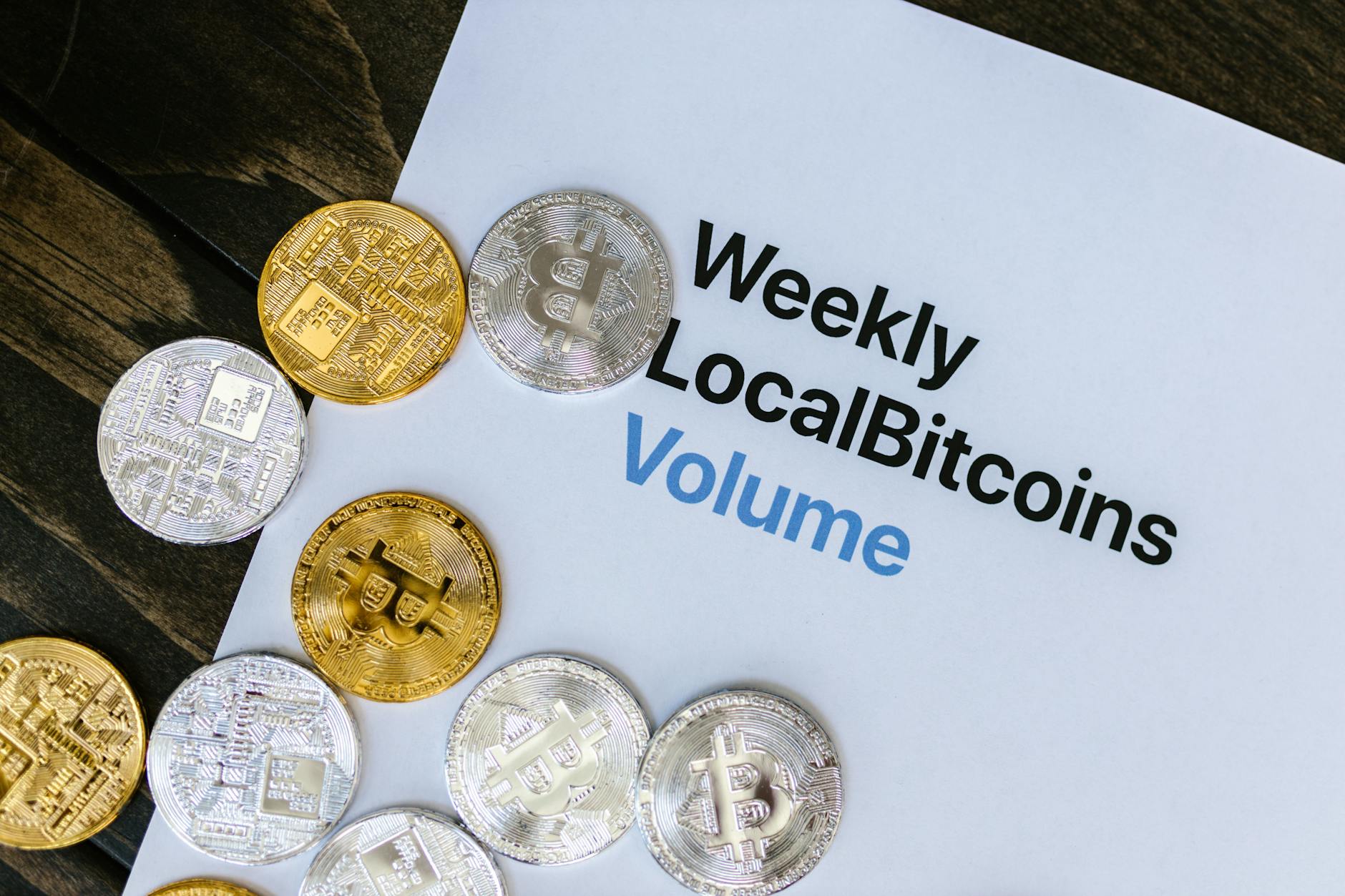 Silver and Golden Bitcoin Tokens Scattered over a Finance Report