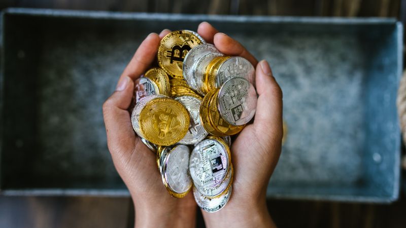 Close-up of hands holding gold and silver cryptocurrency coins, symbolizing digital investment.