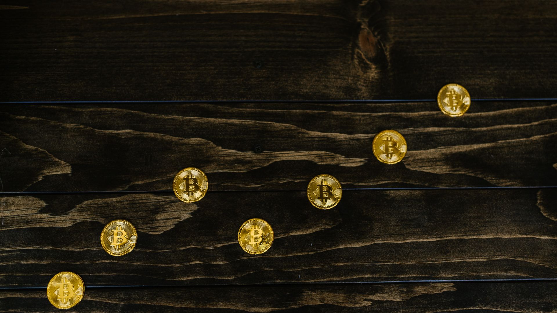 Gold-colored bitcoins arranged diagonally on a dark wooden surface — modafinil bitcoin payment