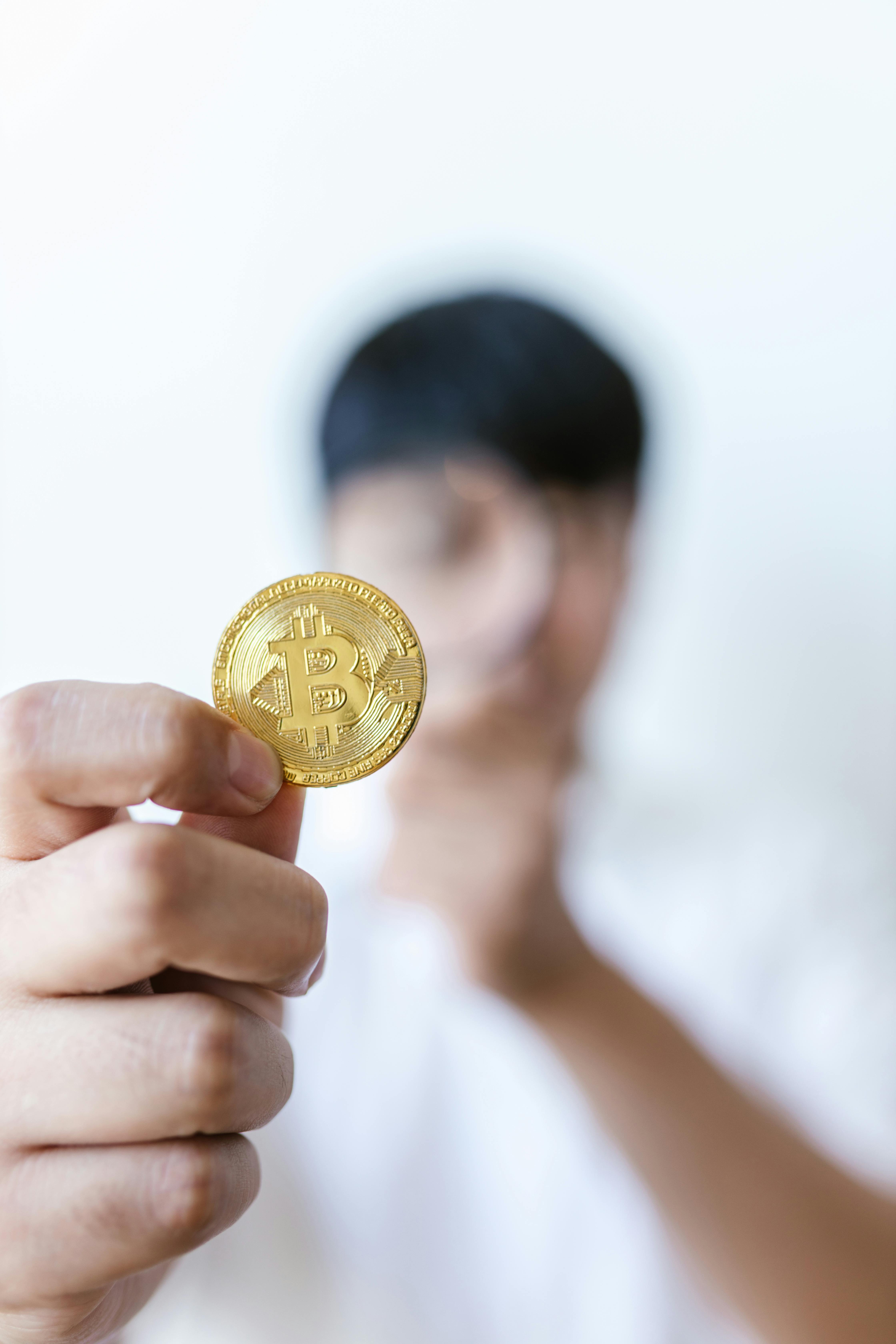 man in white shirt holding gold round coin
