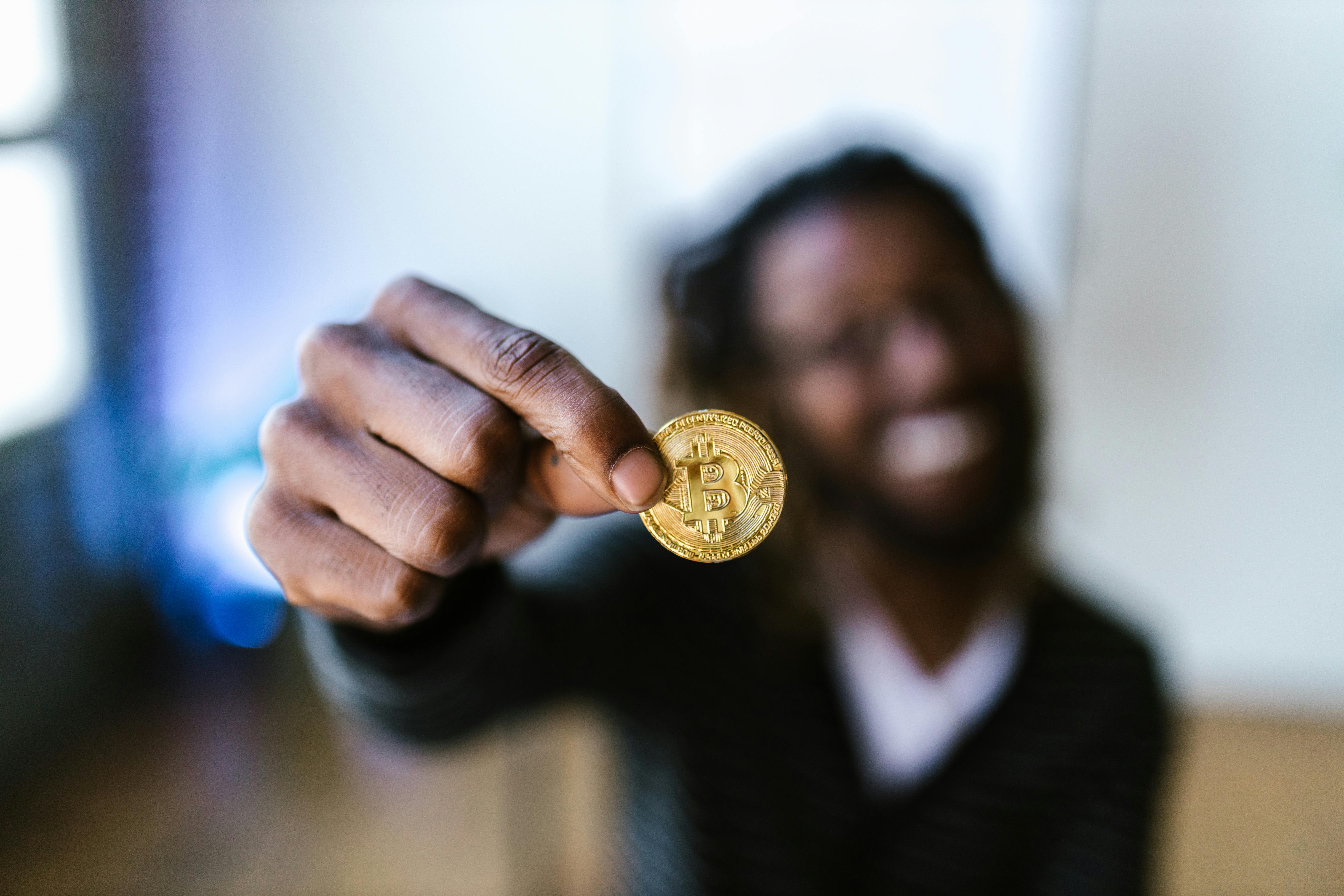 a person holding a gold bitcoin