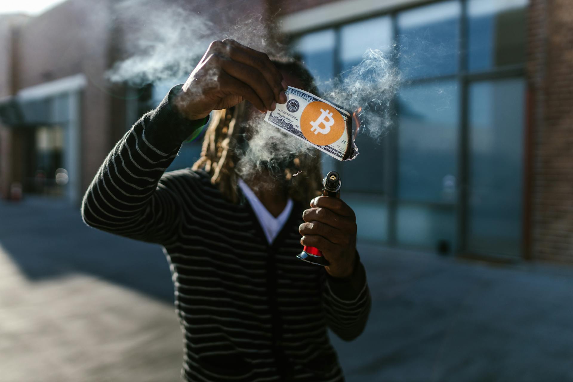 A Person in Stripes Long Sleeves Burning a Dollar with Bitcoin Sign