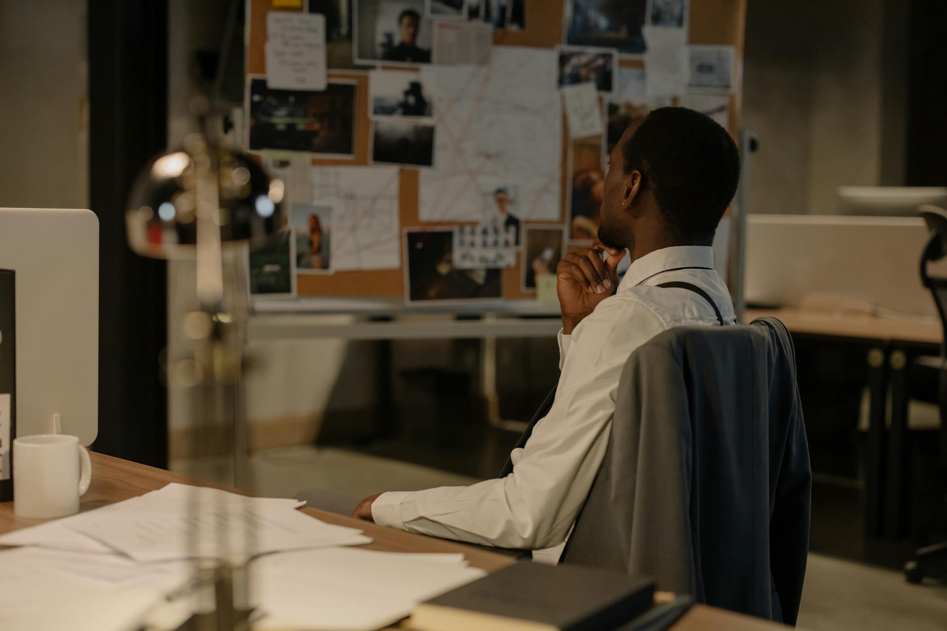 A Man Sitting on a Swivel Chair while Looking at the Photos on the Board