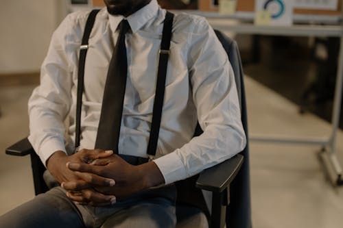 Man in White Shirt and Black Necktie Sitting on Black Chair