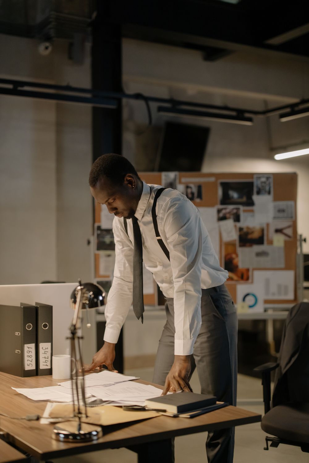 Investigator standing over case paperwork in a quiet office