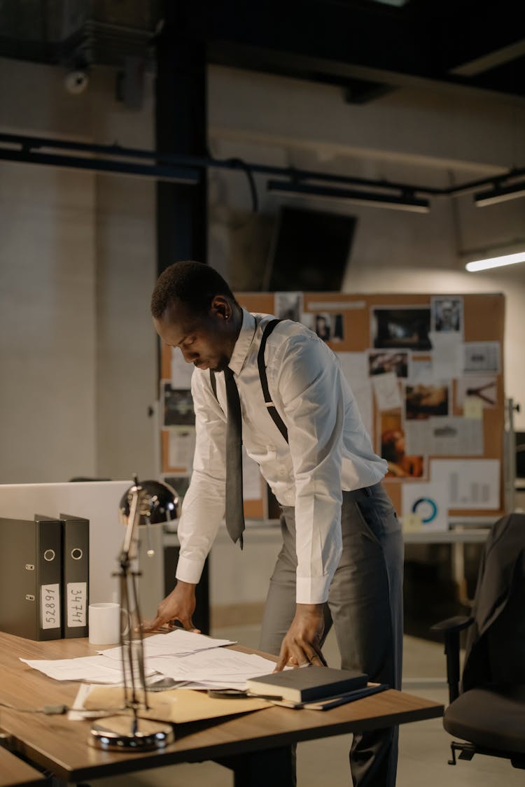 Man In White Shirt And Black Necktie Standing In Front Of Desk