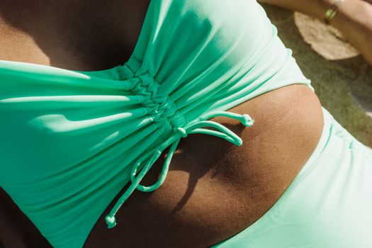 Close-up of a teal swimsuit on a sandy beach, capturing a relaxing summer vibe.