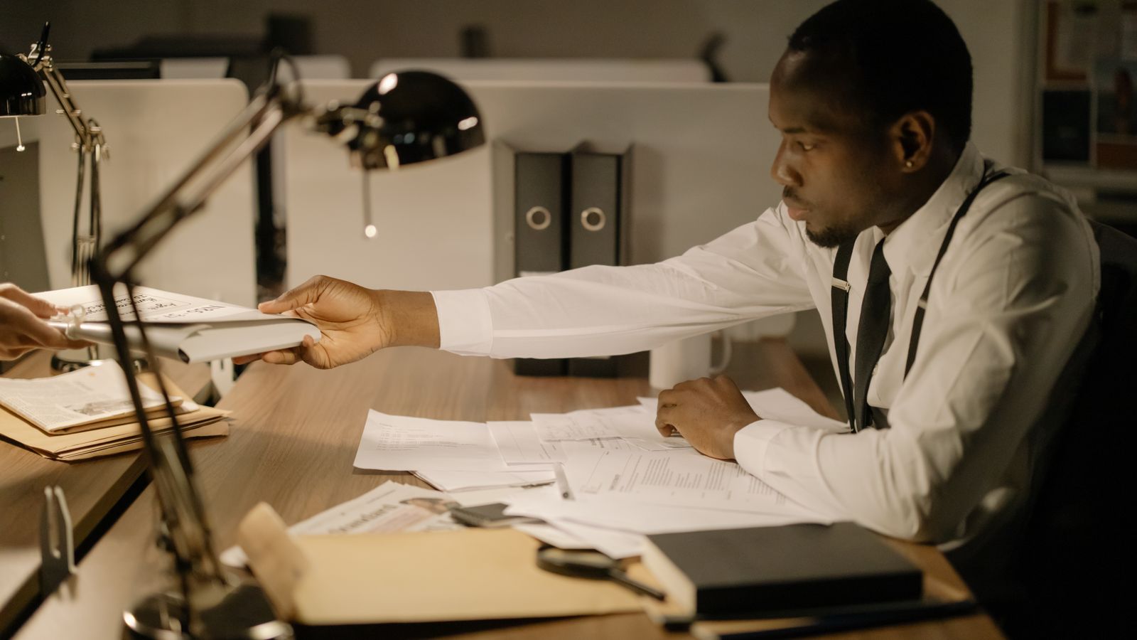 A focused professional man in an office exchanging documents while working late.