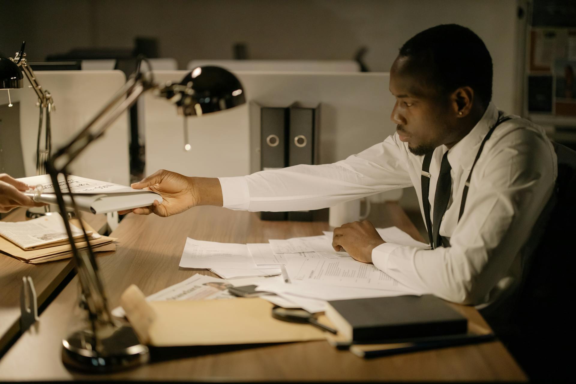 A focused professional man in an office exchanging documents while working late.