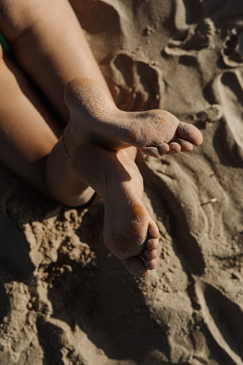 Close Up Photo of Person's Feet Covered with Sand