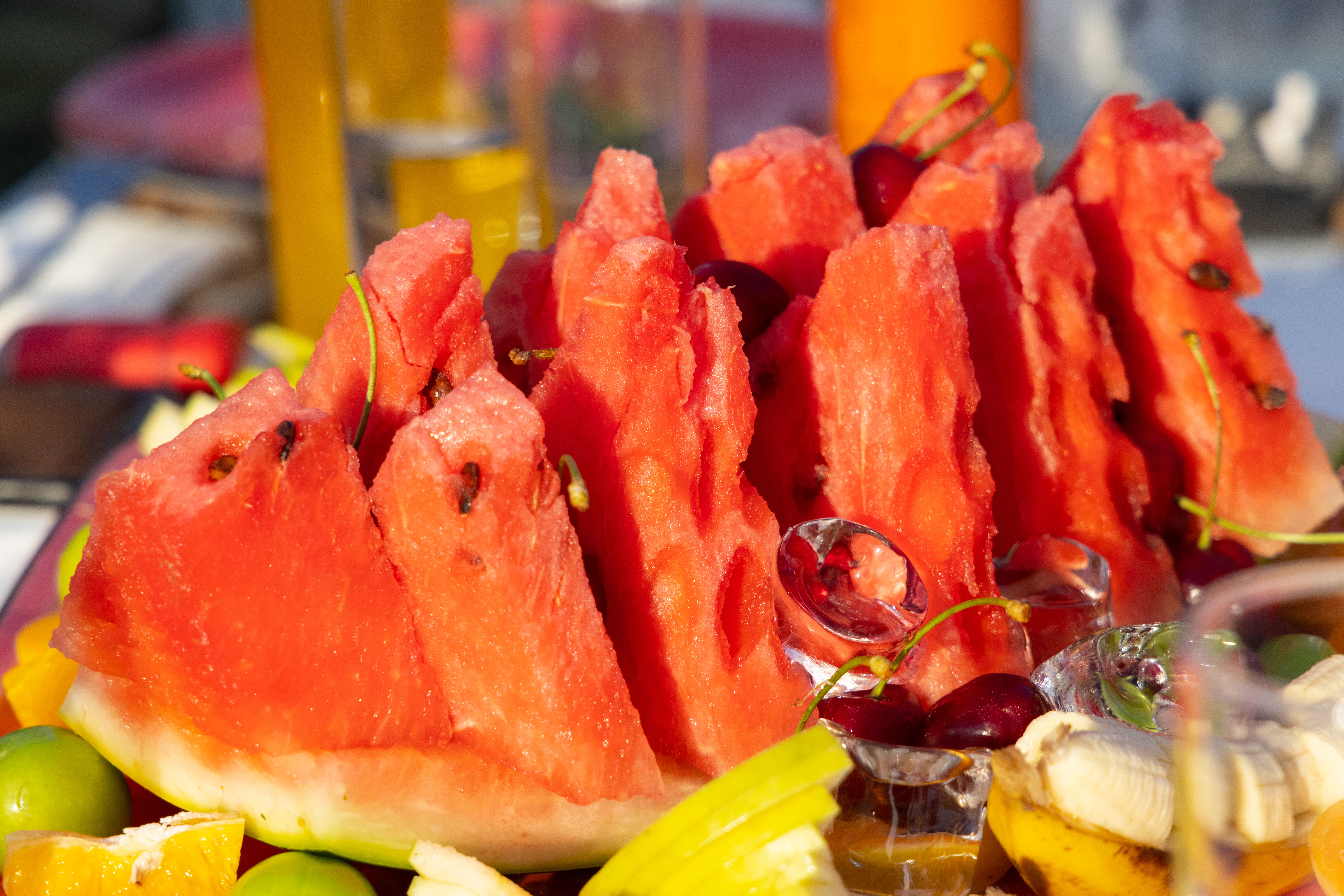 Vibrant sliced watermelon surrounded by fresh fruits set for a summertime picnic.