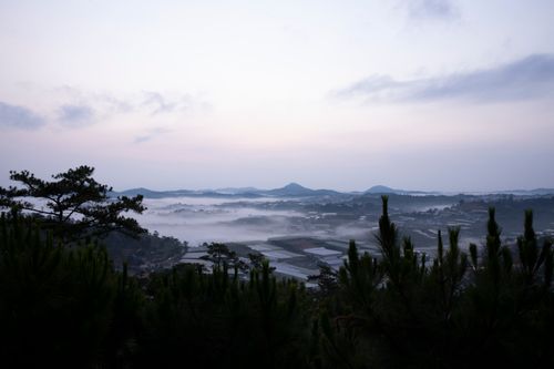 Free A tranquil valley landscape enveloped in morning mist with distant hills. Stock Photo