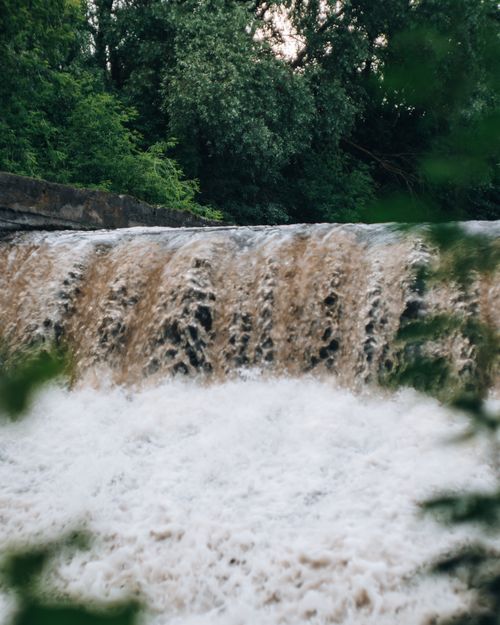Free Peaceful scene of a cascading waterfall surrounded by green foliage. Stock Photo