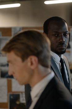 Two businessmen in formal suits engaged in a serious discussion in an office setting.