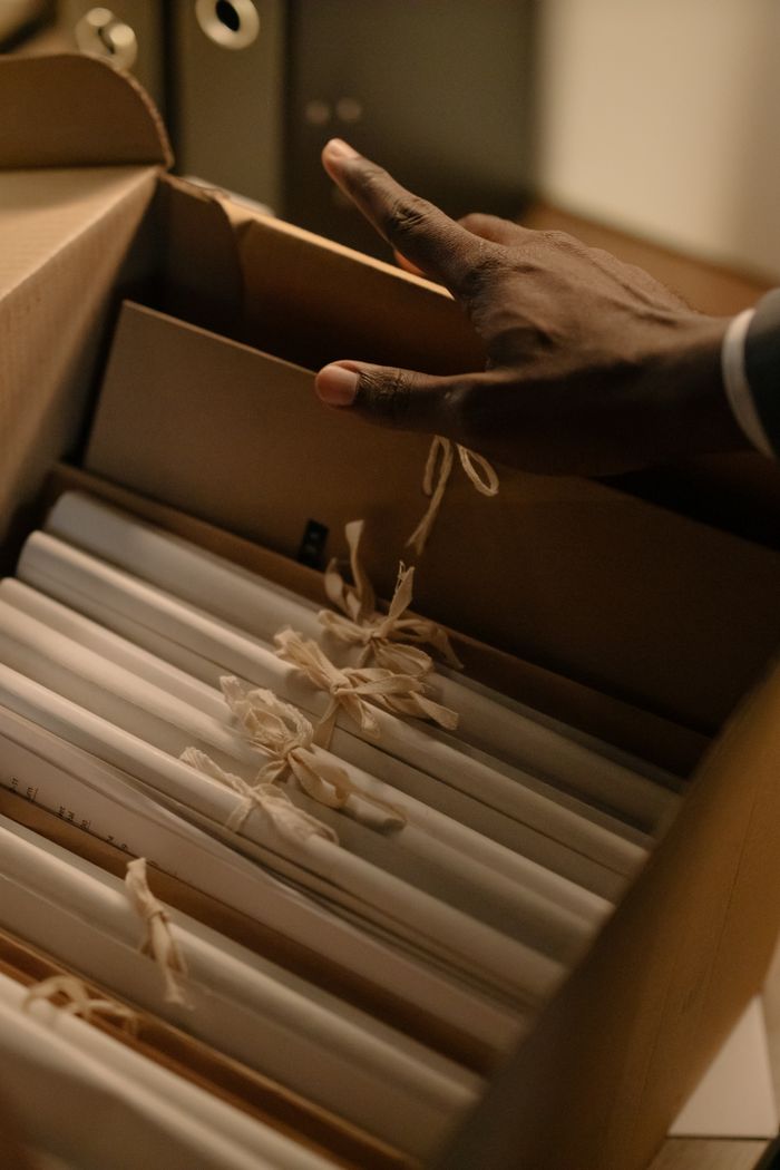 Hand retrieving tied documents from an official archive box, representing military records correction