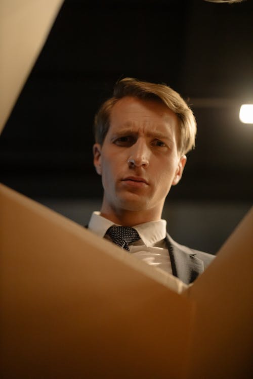 Man in Gray Suit Jacket Looking Inside the Box