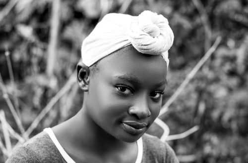 Free A grayscale close-up of a smiling girl with a headwrap, capturing innocence and beauty. Stock Photo