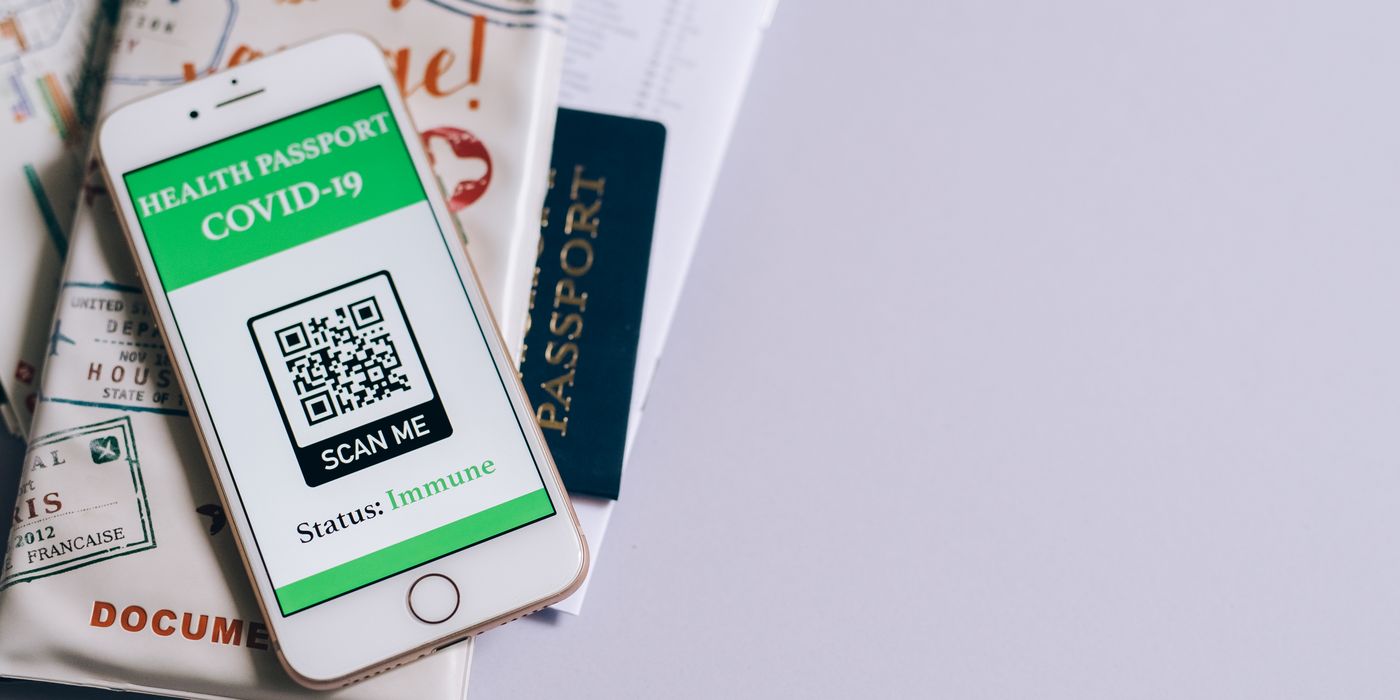 A smartphone with a COVID-19 health passport, passport, and travel documents indicating readiness for international travel.