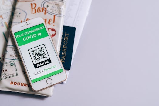 A smartphone with a COVID-19 health passport, passport, and travel documents indicating readiness for international travel.