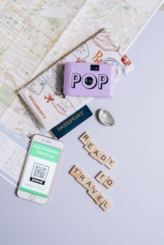 Flat lay of travel essentials featuring a health passport, map, and camera set for travel readiness.