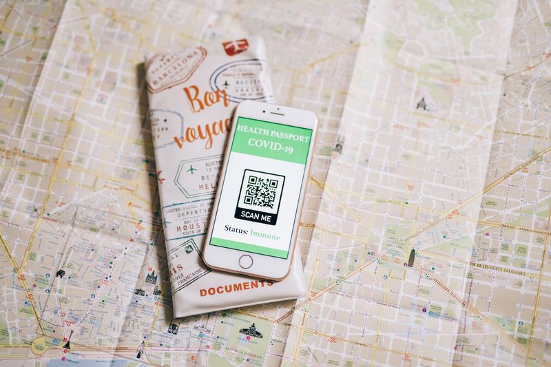 Top view of a smartphone with COVID-19 health passport and travel documents on a map.