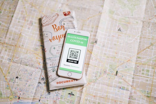 Top view of a smartphone with COVID-19 health passport and travel documents on a map.