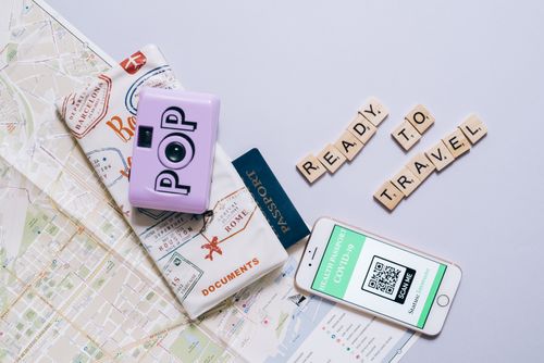 Free Travel essentials including a map, passport, camera, and smartphone with COVID-19 health passport for modern travel preparations. Stock Photo